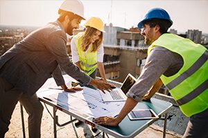 Three people in hard hats and vests looking at a table.